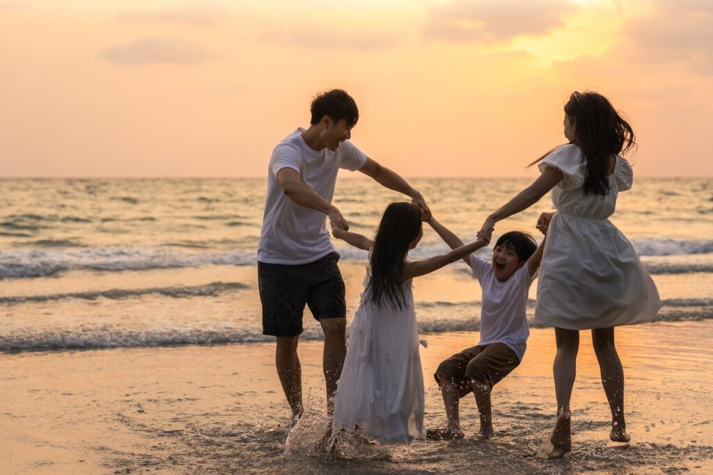 Asian Young Happy Family Enjoy Vacation On Beach In The Evening.